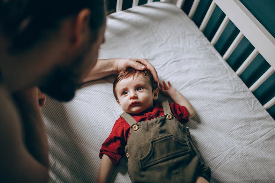 imagen de un bebé durmiendo en una cuna mientras un padre lo revisa