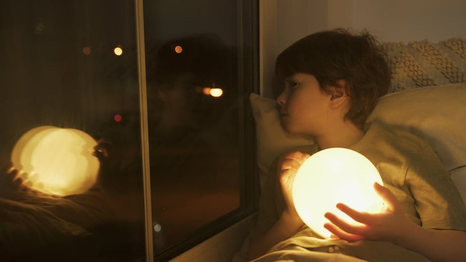 Niño durmiendo en una habitación oscura y tranquila con un peluche, un libro de cuentos y una luz nocturna
