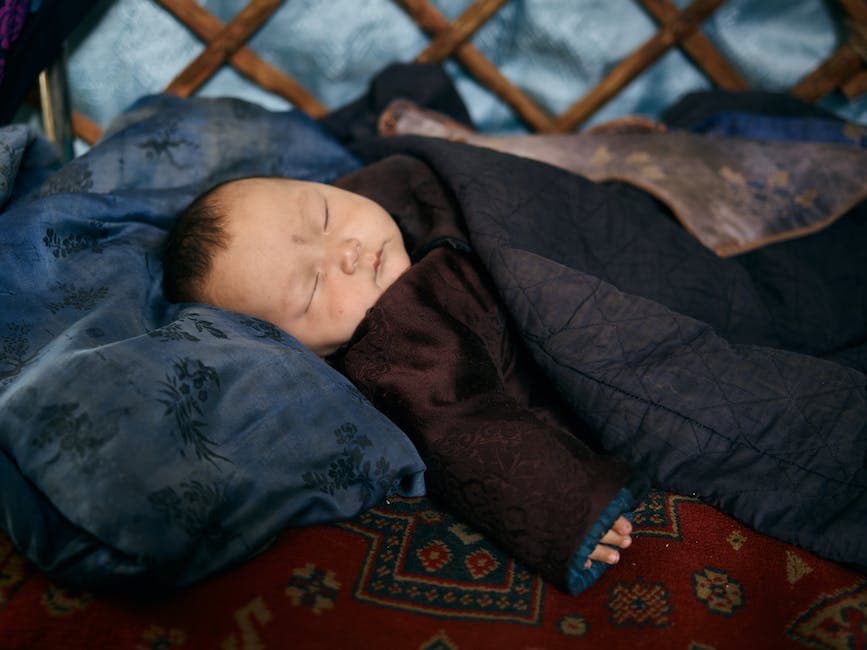 Bebé durmiendo en la cuna cubierto de una manta